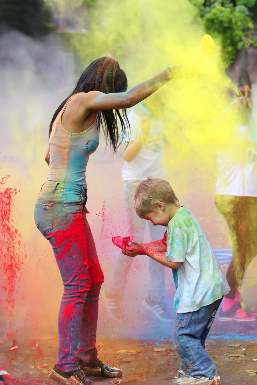 Une jeune-femme qui jette de la poudre colorée en l'air, un enfant fait la même chose juste devant elle. ©2020 Mathieu Improvisato